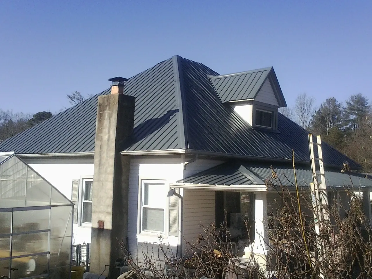 Dark blue standing seam metal roof on a white farmhouse with dormer — Slate & Tile Roof Repair by Roofing Brothers in Okeana