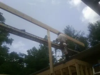 Carpenter setting a ridge beam over a new addition frame — Ice Dam Removal by Roofing Brothers in Okeana
