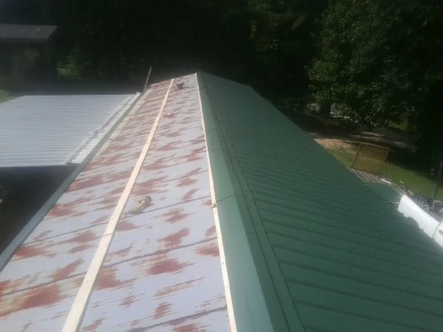 Old rusted panels beside newly installed green metal roofing — Wind Damage Roof Repair by Roofing Brothers in Okeana