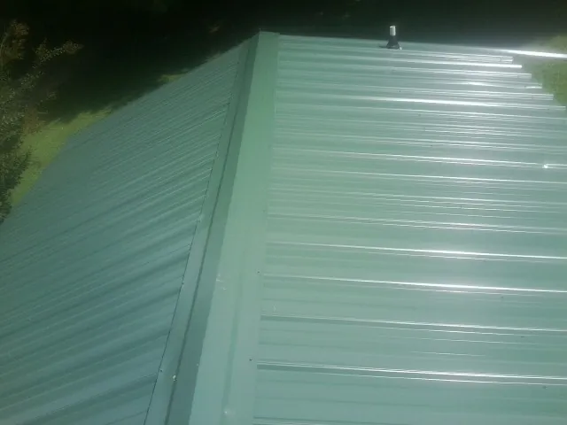 New green metal panels meeting at the ridge of a roof in Okeana