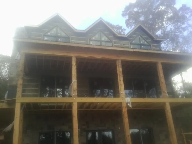 Dormers and porch framing on a large log home under construction — Roof Coating work by our crew in Okeana