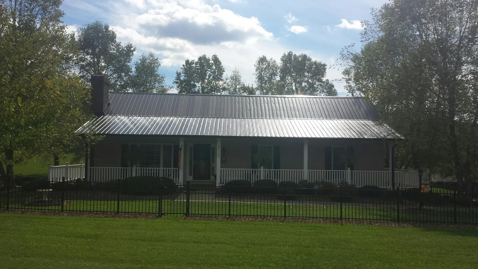 Gray metal roof on a brick ranch with a full width front porch — Gutter Guard Installation work by our crew in Okeana
