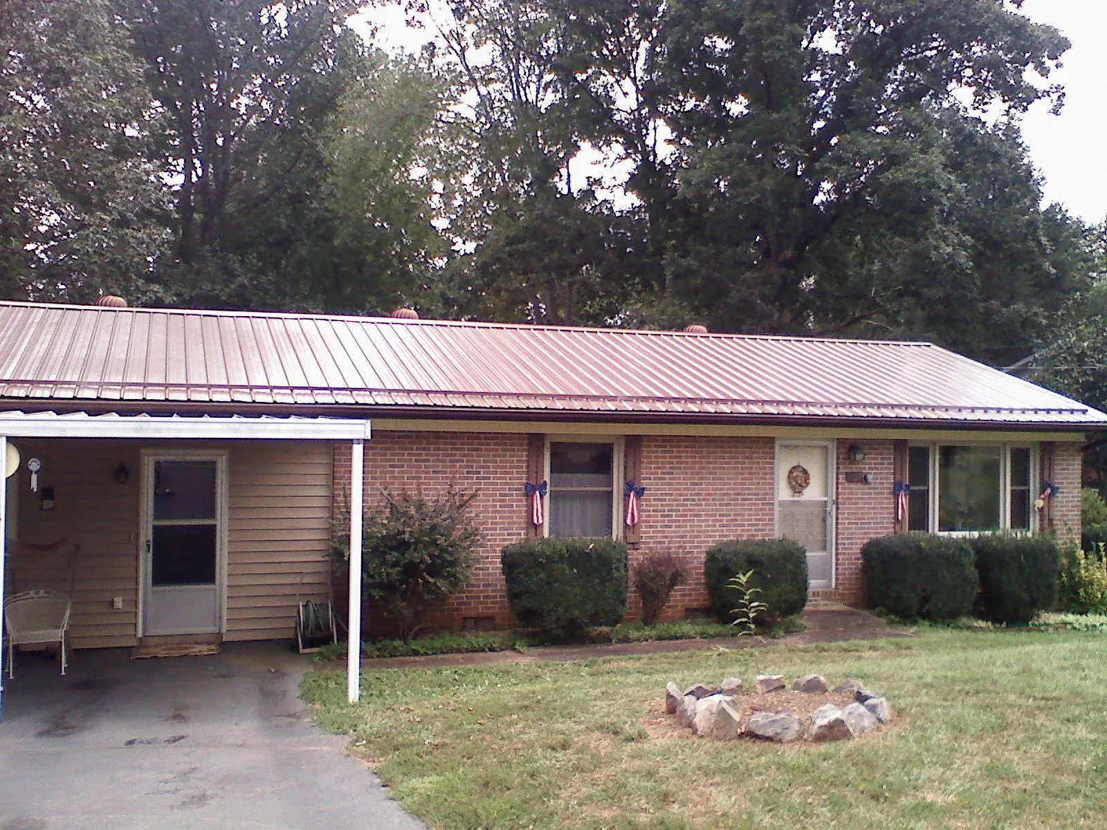Bronze metal roof and carport on a brick ranch home — Roof Repair work by our crew in Okeana